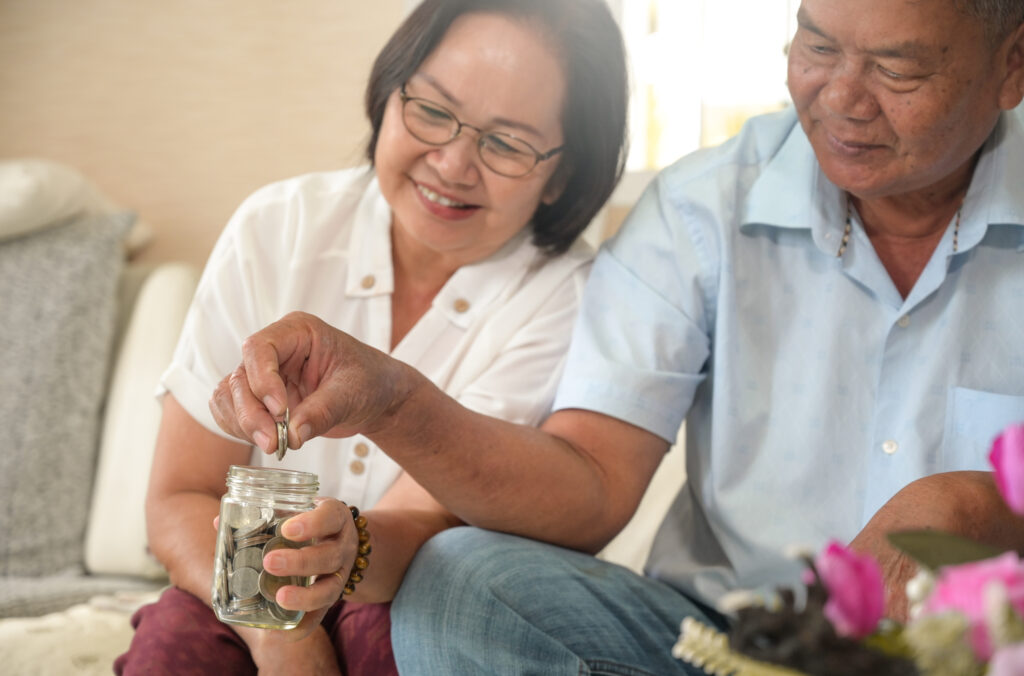 Photo of Asian couple saving money in a jar - Maxing out your employer's plans is a critical step in the FOO system by Money Guy